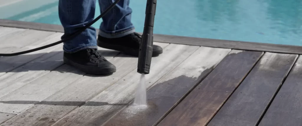 a Kärcher pressure washer being used to clean a poolside wood deck