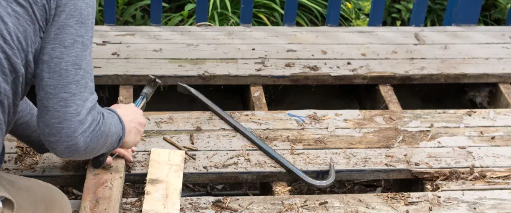 a crowbar or pry bar being used to remove rotten deck boards