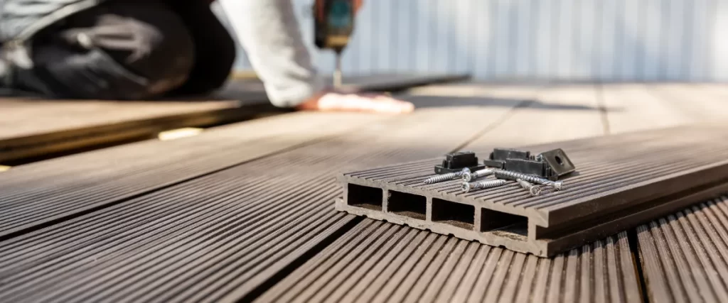 a deck builder installing brown wood composite decking boards