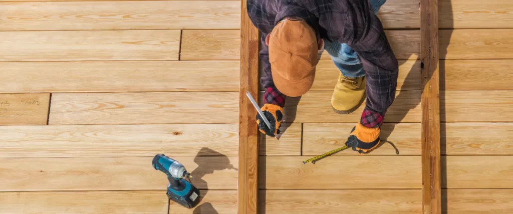 a deck builder installing wooden decking boards using cedar or pressure-treated lumber