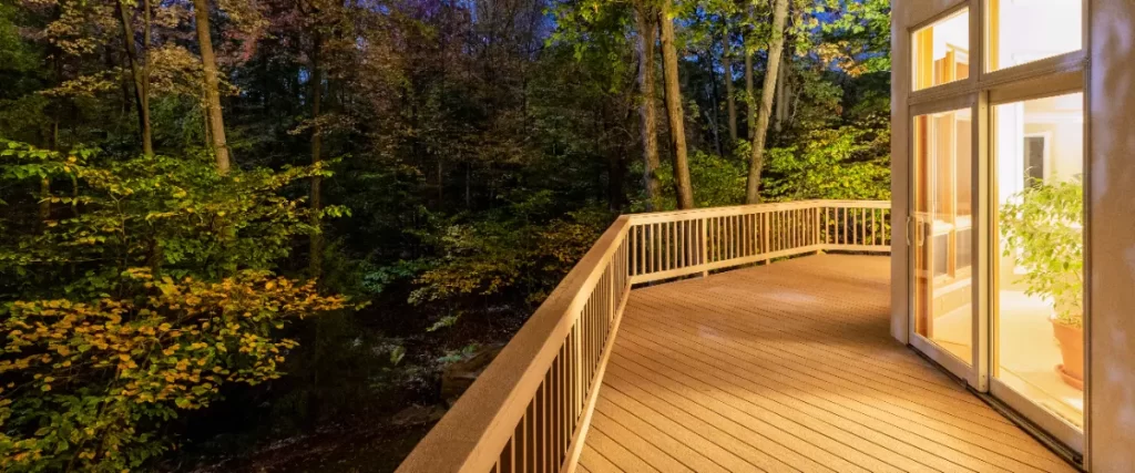 a low-maintenance composite wood deck at nighttime with trees all around