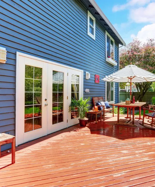 Large cedar wood deck with white French doors and blue lap siding installed by deck building companies in Nashville, TN.
