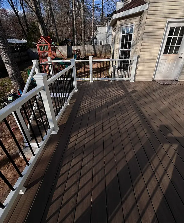 Elevated composite backyard deck with white railing and black aluminum balusters