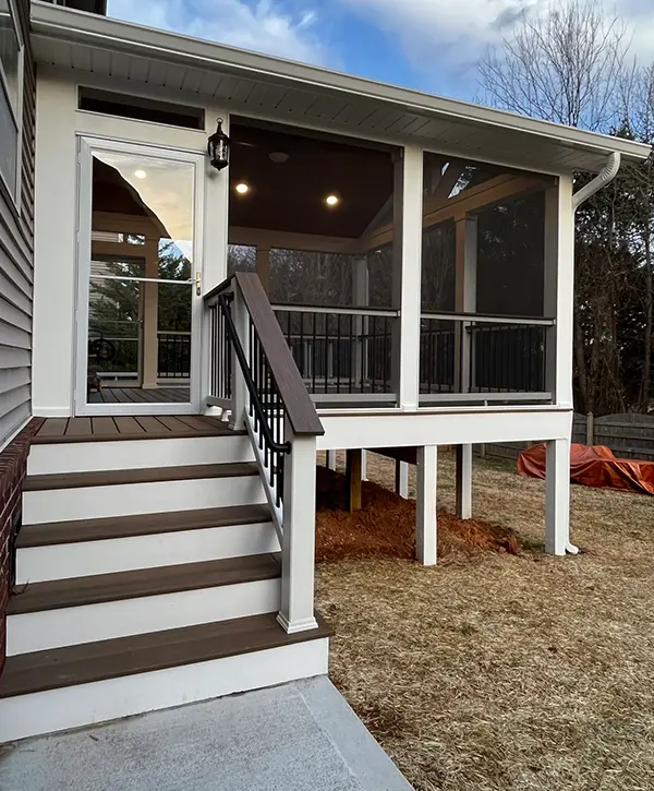 Elevated screened porch with composite stairs and black aluminum railing on custom backyard deck