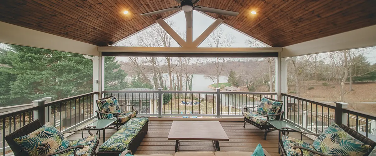 Screened-in covered deck with vaulted wood ceiling and outdoor seating overlooking backyard landscape